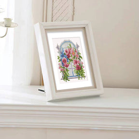 FloraleFenster diamond painting set in white frame, displayed on a white table, showcasing vibrant mini art of flowers.