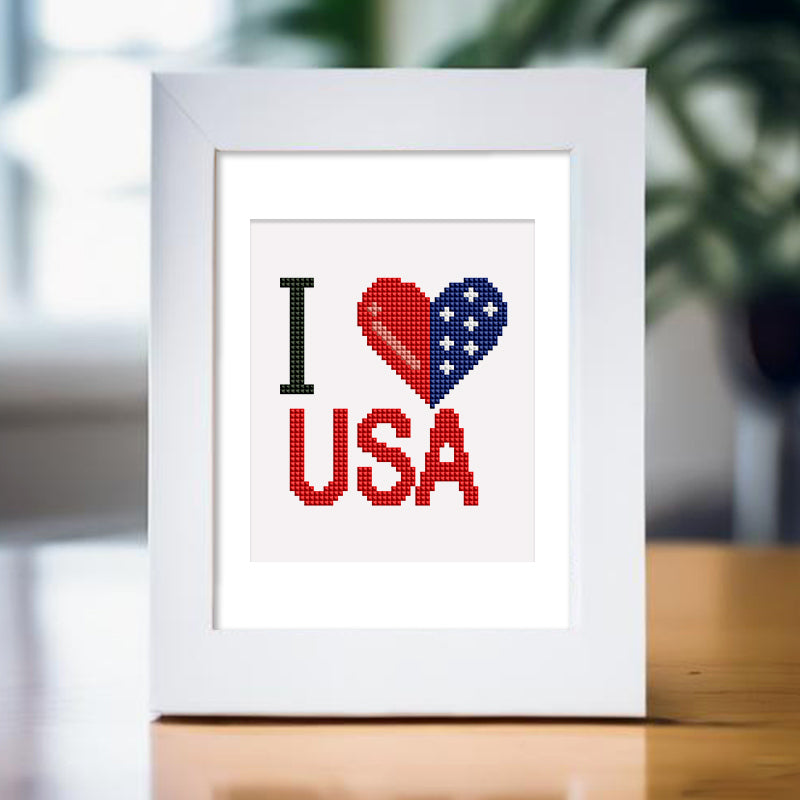 Framed USA-themed diamond painting with "I Love USA" text in a white frame, showcasing vibrant red, white, and blue colors.