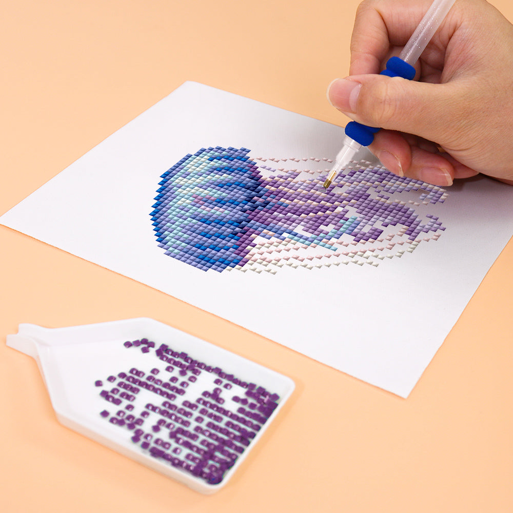 Hand creating ocean-themed diamond painting art with purple and blue gems, part of Meeresbewohner 12er SET - Mini Kunst.