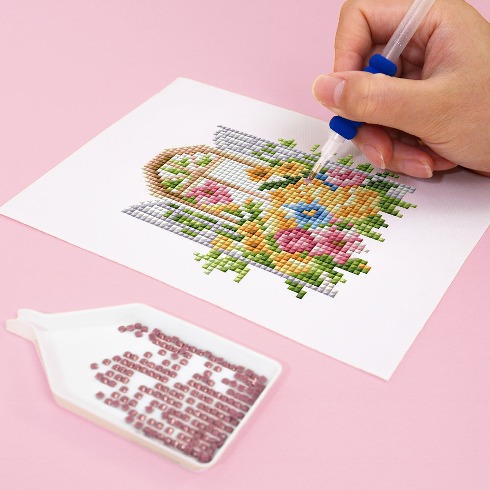 Hand creating floral diamond painting art on canvas with pink background, showcasing vibrant miniature artwork technique (Mini Kunst)