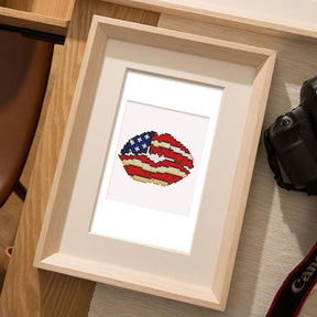 Framed diamond painting of lips with USA flag design, showcasing mini kunst art on a wooden table.