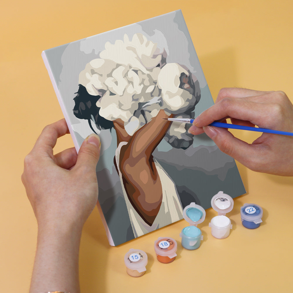 Person painting a Blumenhaar Edition Zwei artwork with numbered paints and brush, part of a 6-piece mini art set.