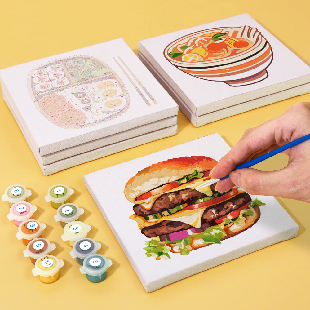 Person painting a burger canvas from the Küchen Edition Zwei 6er SET - Malen nach Zahlen with paint pots included, mini art for kitchen decor.