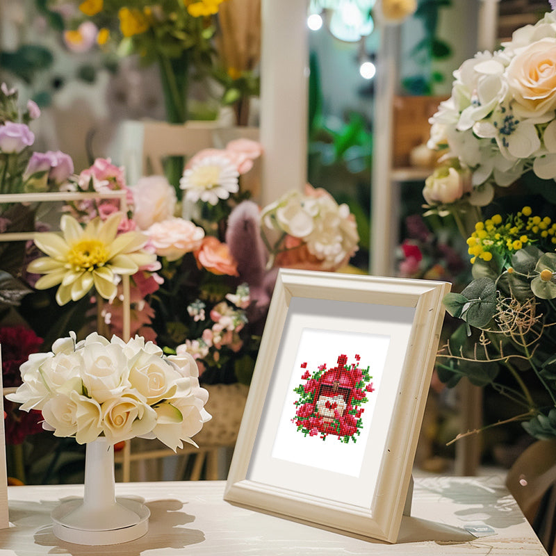 Framed diamond painting of a heart with roses on a table surrounded by various colorful flowers, promoting mini kunst.